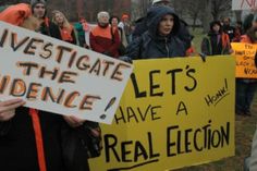 many people are holding signs and protesting in front of a building with orange writing on them