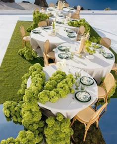 an outdoor dining area with tables and chairs covered in white tablecloths, surrounded by grass