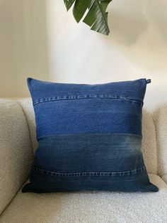 a blue pillow sitting on top of a white couch next to a potted plant