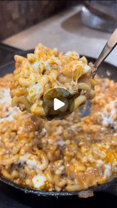 a spoon full of macaroni and cheese being lifted from a skillet