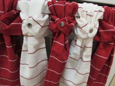 three red and white towels hanging on the side of a window sill with buttons