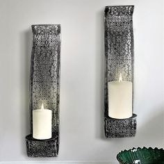 two metal wall sconces with candles on them