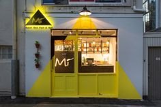 a yellow and black store front with the door open at night time, it's lit up