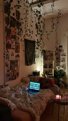 a laptop computer sitting on top of a bed next to a plant hanging from the ceiling