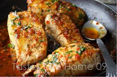 some meat is cooking in a skillet with sauce on the side and a spoon next to it