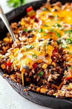 a skillet filled with mexican rice and beans, topped with a cheesy sauce