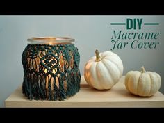 two white pumpkins sitting on top of a wooden table next to a candle holder