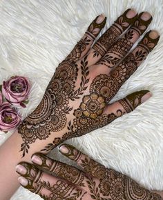 two hands with henna tattoos on them and flowers in the middle of each hand