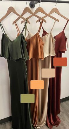 four dresses hanging on a rack in front of a wall with color swatches to choose from