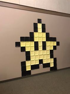 a yellow and black wall hanging on the side of a gray wall next to a carpeted floor