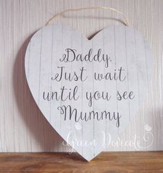 a wooden heart hanging on a wall with the words daddy, just wait until you see mommy