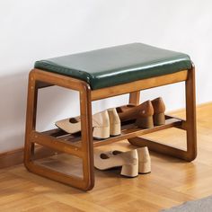 a wooden bench with several pairs of shoes under it on the floor next to a wall