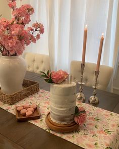 a table topped with a white cake and pink flowers