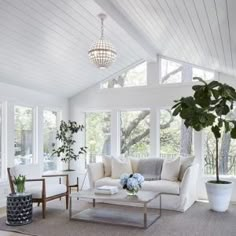 a living room filled with furniture and a chandelier hanging from the rafters