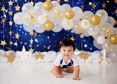 a baby is laying on the floor in front of balloons