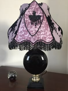 a lamp that is sitting on top of a table next to a glass ball with a tassel