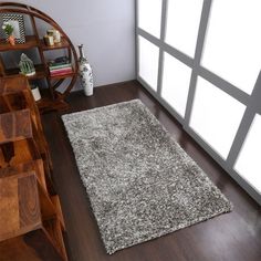 an area rug is placed on the floor in front of a book shelf and window