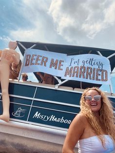 a woman standing in front of a boat that says beer me married on the side