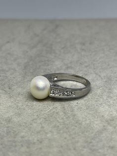 This is a beautiful handmade natural freshwater pearl & CZ sterling silver ring that is size 7. This ring features a natural freshwater pearls that measures approximately 10 MM in size as well as 10 Cubic Zirconia stones on the sides of the band. This ring is also stamped 925 on the inside of the ring. Pearl is the gemstone associated with the month of June. This ring is handmade and one of a kind. This item is new and unworn. Silver Akoya Pearl Ring With Pearl Drop, Silver Akoya Pearl Drop Ring, Silver Ring With Pearl Charm, Silver Pearl Ring With Pearl Drop, Silver Pearl Drop Ring, Silver Rings With Pearl Charm, Silver Pearl Drop Ring For Anniversary, Silver Akoya Pearl Ring, Ring Pearl