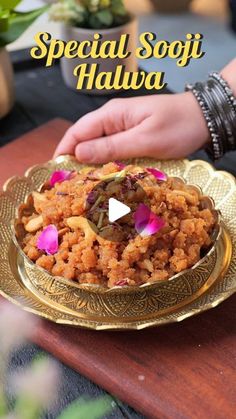 a person is serving food on a gold plate with pink flowers in the center and words special sofit halwa written above it