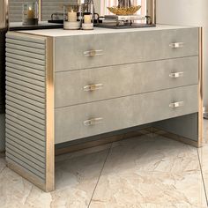 a metallic dresser with two candles on top and a mirror in the corner above it