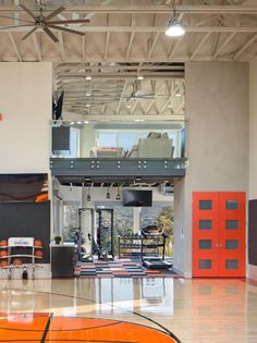 an indoor gym with orange and black basketballs on the floor in front of it