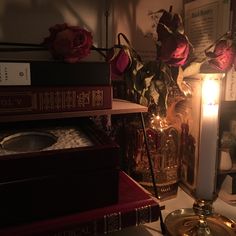 a candle is lit in front of some books and other items on a table with flowers