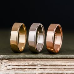 three different colored wedding bands sitting on top of a book