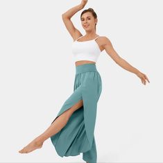 a woman in a white tank top and teal green skirt is dancing with her legs spread out