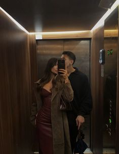 a man and woman taking a selfie in an elevator