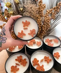 a person is holding six small tins filled with cookies and marshmallows