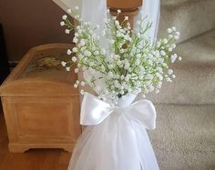 a vase filled with white flowers sitting on top of a wooden table next to stairs