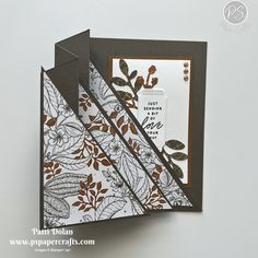 a close up of two folded cards on a white surface with brown and black accents