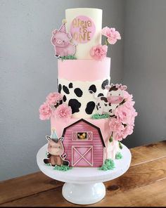 a pink and white cake with farm animals on it's side, sitting on top of a wooden table