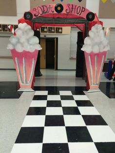 two giant cupcakes are on the floor in front of a sign that says soda shop