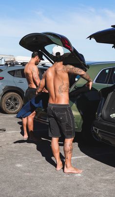 two men standing in the parking lot with their cars open and one man has his back to the camera