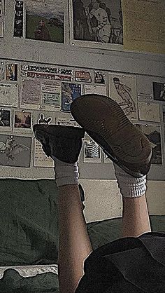 a person laying down with their feet up in the air on a bed covered by posters