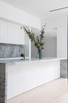 two vases filled with flowers on top of a marble counter next to a sink