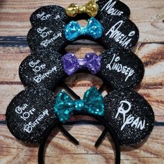 mickey mouse ears with name on them and two bows in the middle, sitting on top of a wooden table