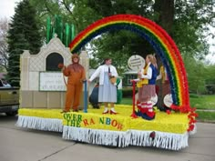 people standing on top of a float with a rainbow decoration in the middle of it