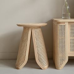 two wooden stools sitting next to each other near a vase with flowers in it