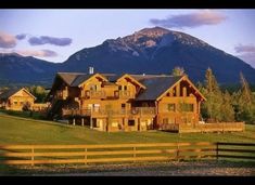 a large wooden house sitting on top of a lush green field next to a mountain