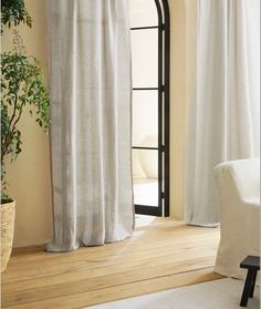 a living room with white curtains and a potted plant