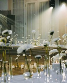 white flowers are in vases on a table