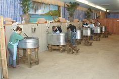 people are sitting in large metal buckets at the counter and one person is standing behind them