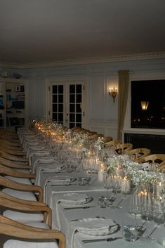 the long table is set with many glasses and candles