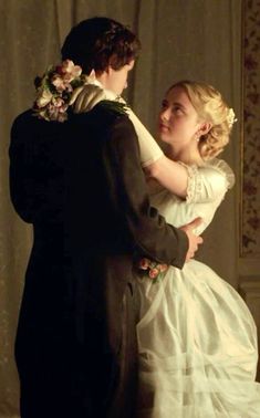 a man and woman dressed in period clothing standing next to each other with their arms around each other