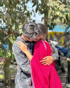 a man and woman embracing each other in front of trees