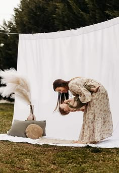 a woman bending down to look at a stuffed animal on a blanket in front of a white backdrop