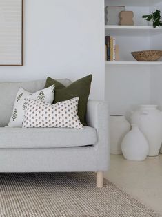 a living room with a gray couch and some white vases